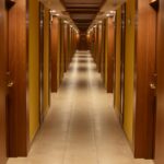 Long hallway view of a modern hotel with wooden doors and ceiling, creating a luxurious ambiance.